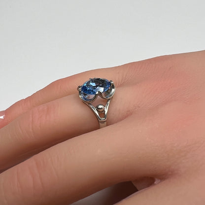 Sterling silver ring with oval blue topaz worn on hand