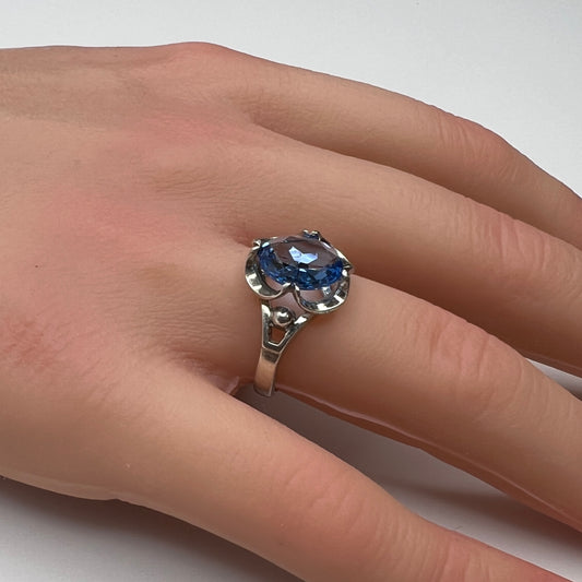 Sterling silver ring with oval blue topaz worn on hand