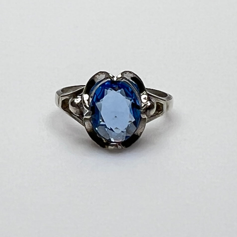 Close-up of vintage silver ring showing blue topaz and sculptural setting