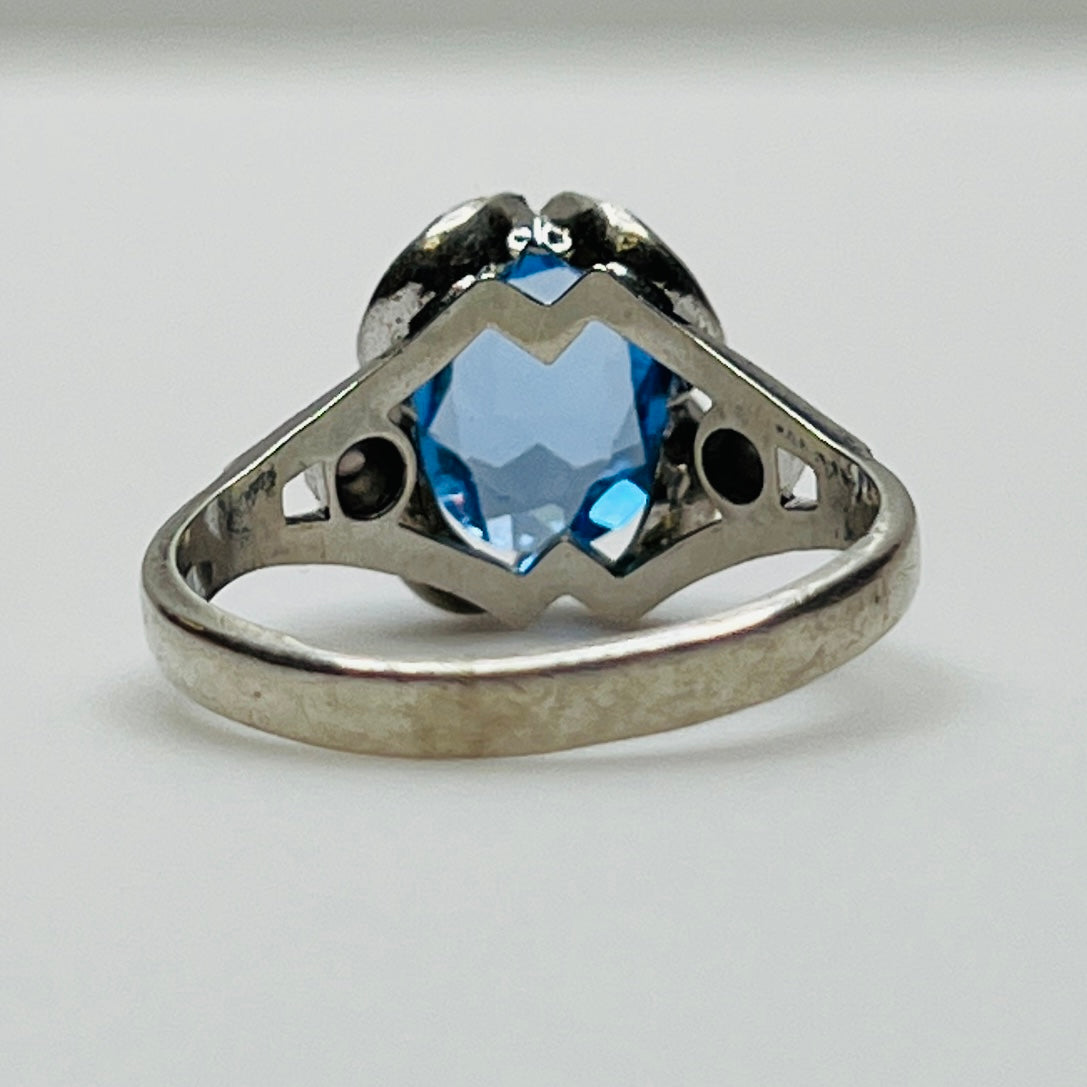 Close-up of vintage silver ring showing blue topaz and sculptural setting