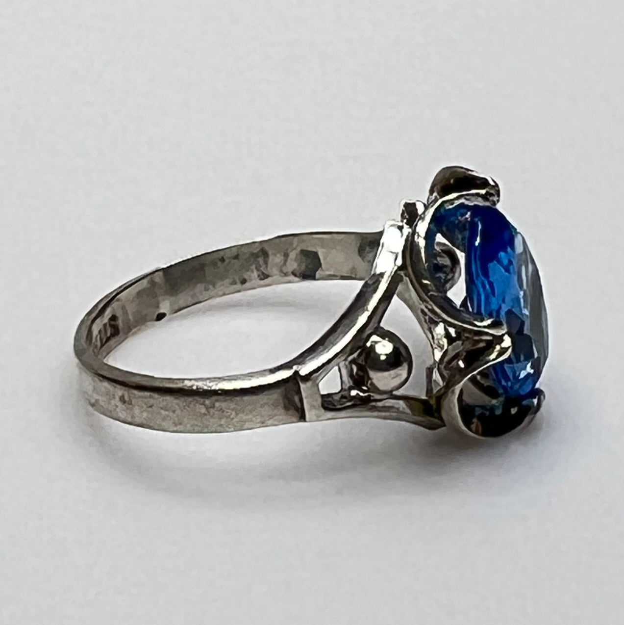 Close-up of vintage silver ring showing blue topaz and sculptural setting