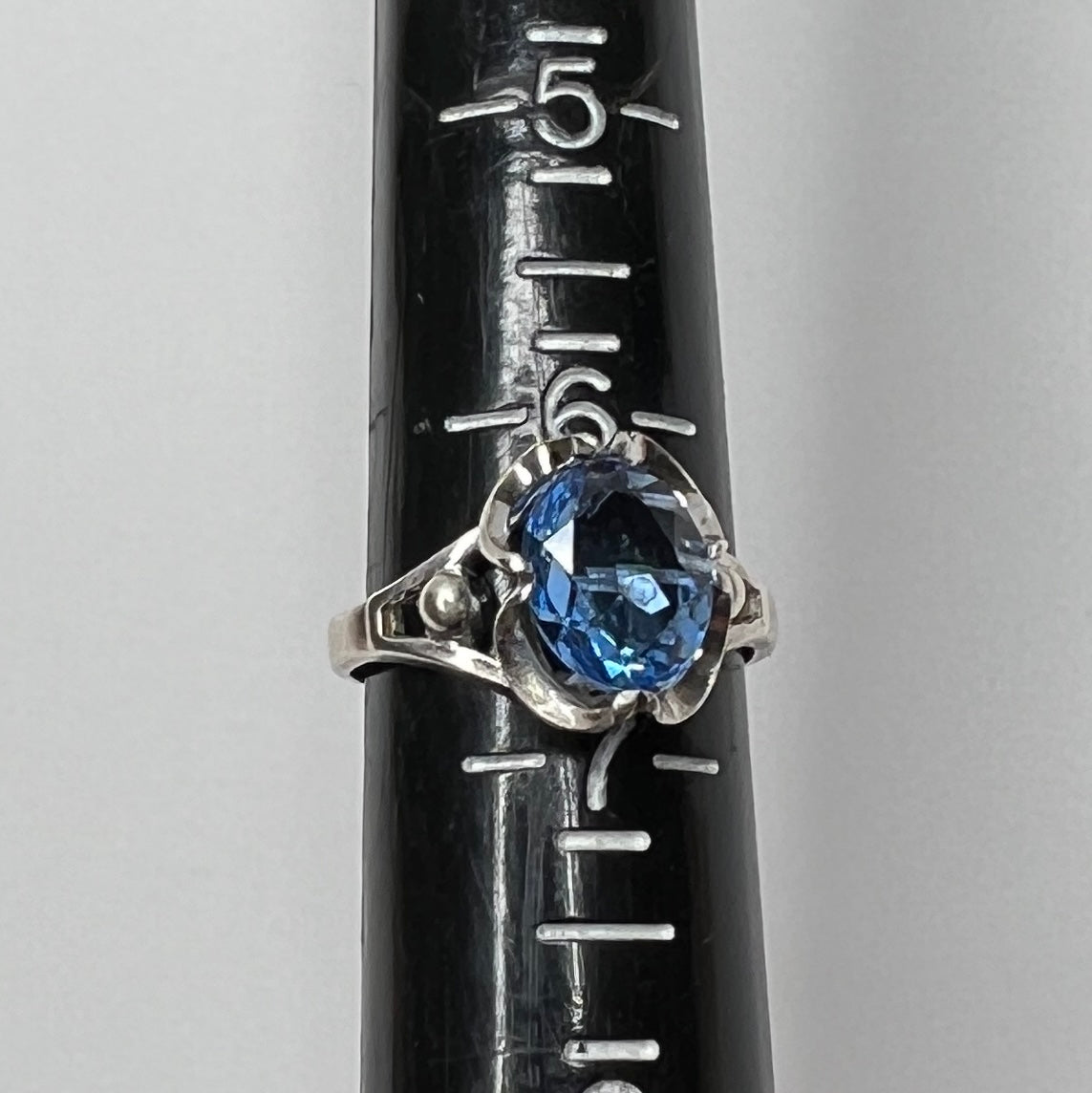 Close-up of vintage silver ring showing blue topaz and sculptural setting