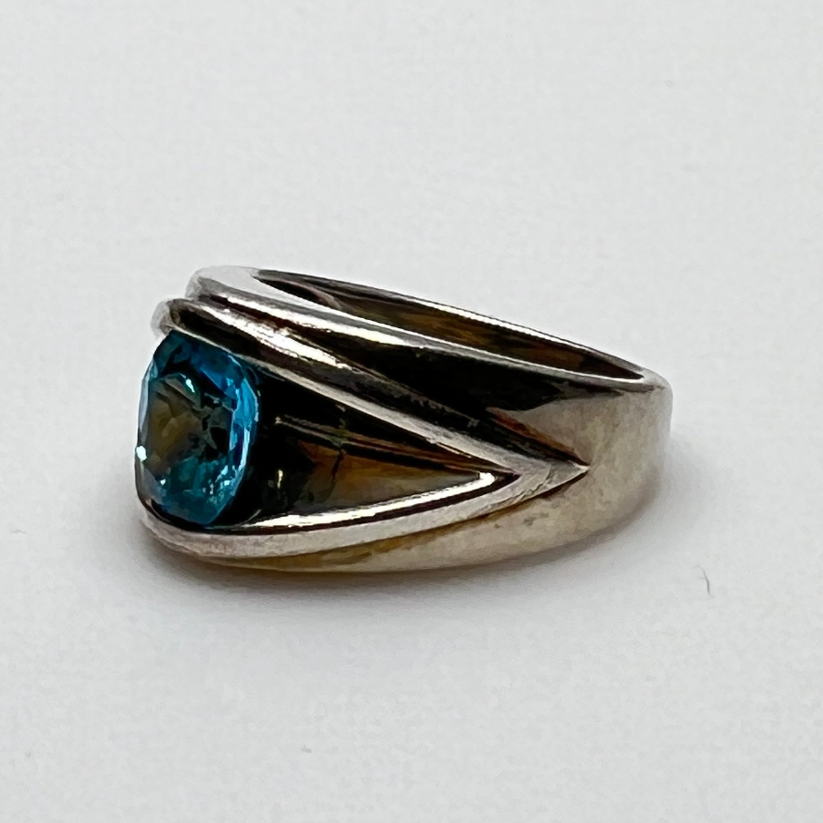 Close-up of bezel-set blue topaz in bold tapered silver band
