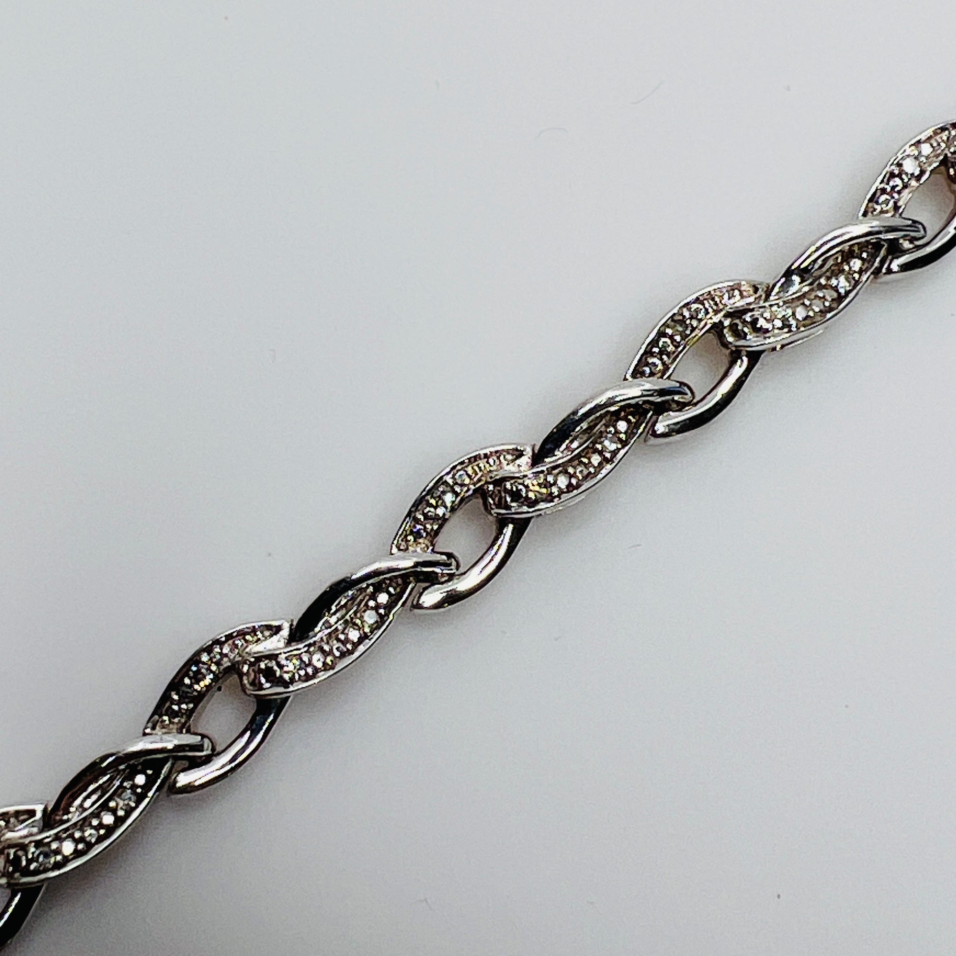 Close-up of diamond-accented links with prong and textured settings