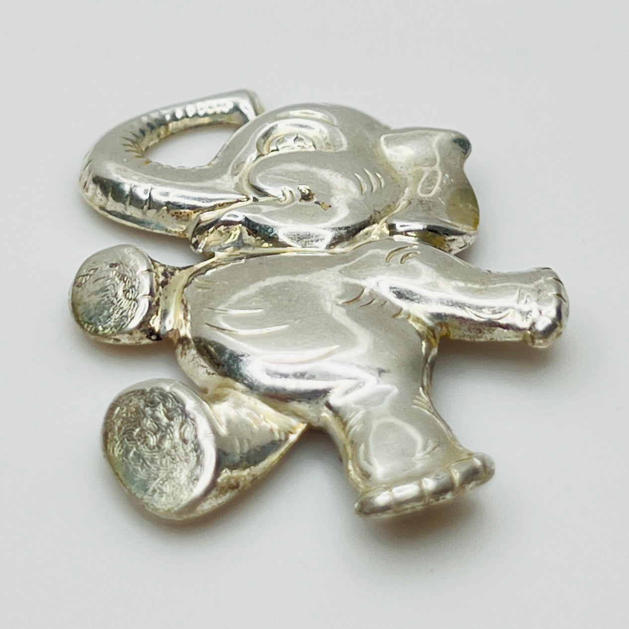 Sterling silver brooch shaped like a walking elephant with raised trunk and rounded limbs