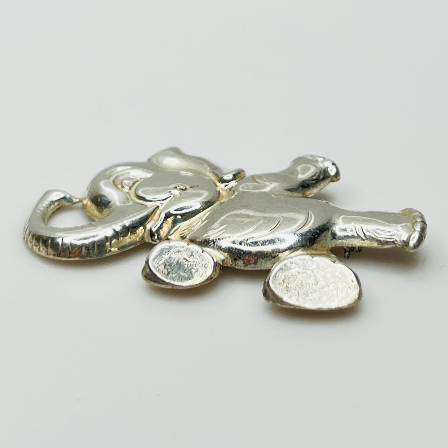 Sterling silver brooch shaped like a walking elephant with raised trunk and rounded limbs