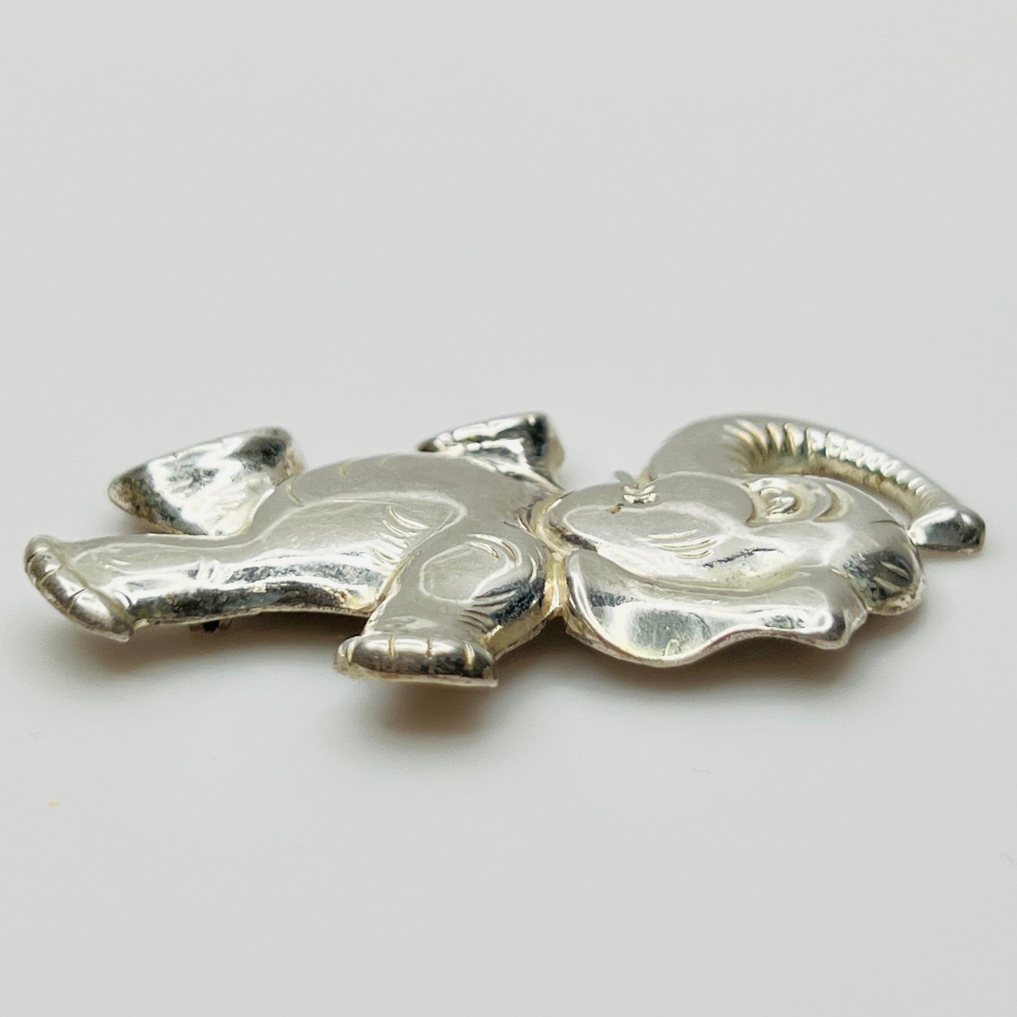 Sterling silver brooch shaped like a walking elephant with raised trunk and rounded limbs