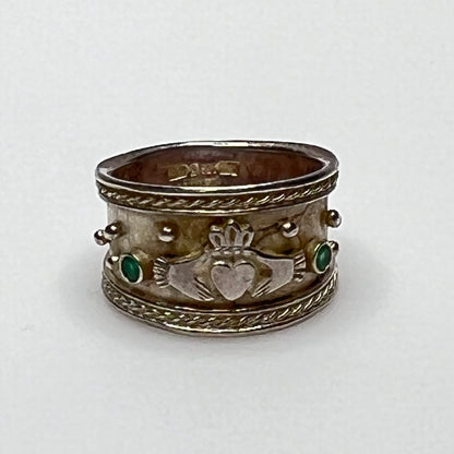Close-up of Claddagh motif and emerald accent on wide silver ring