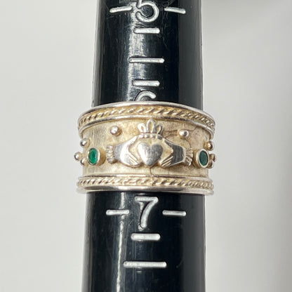 Close-up of Claddagh motif and emerald accent on wide silver ring