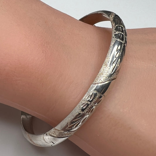 Sterling silver oval bangle shown on wrist with polished floral etching