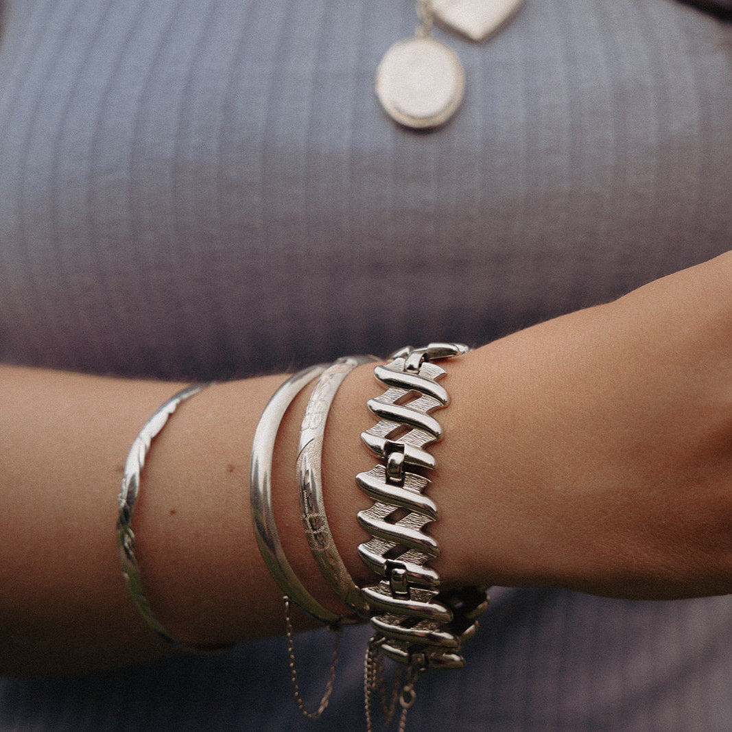 Sterling silver oval bangle shown on wrist with polished floral etching