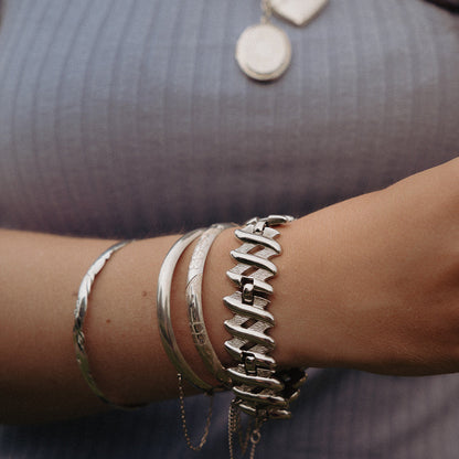 Sterling silver oval bangle shown on wrist with polished floral etching