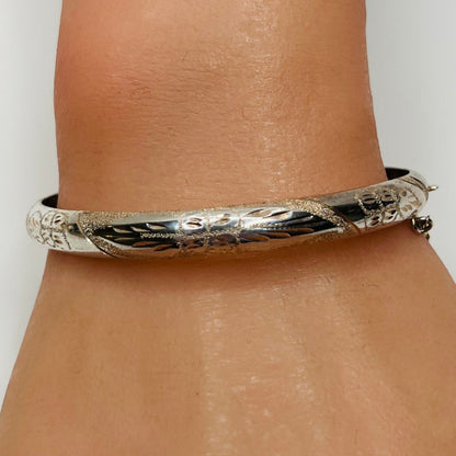 Sterling silver oval bangle shown on wrist with polished floral etching