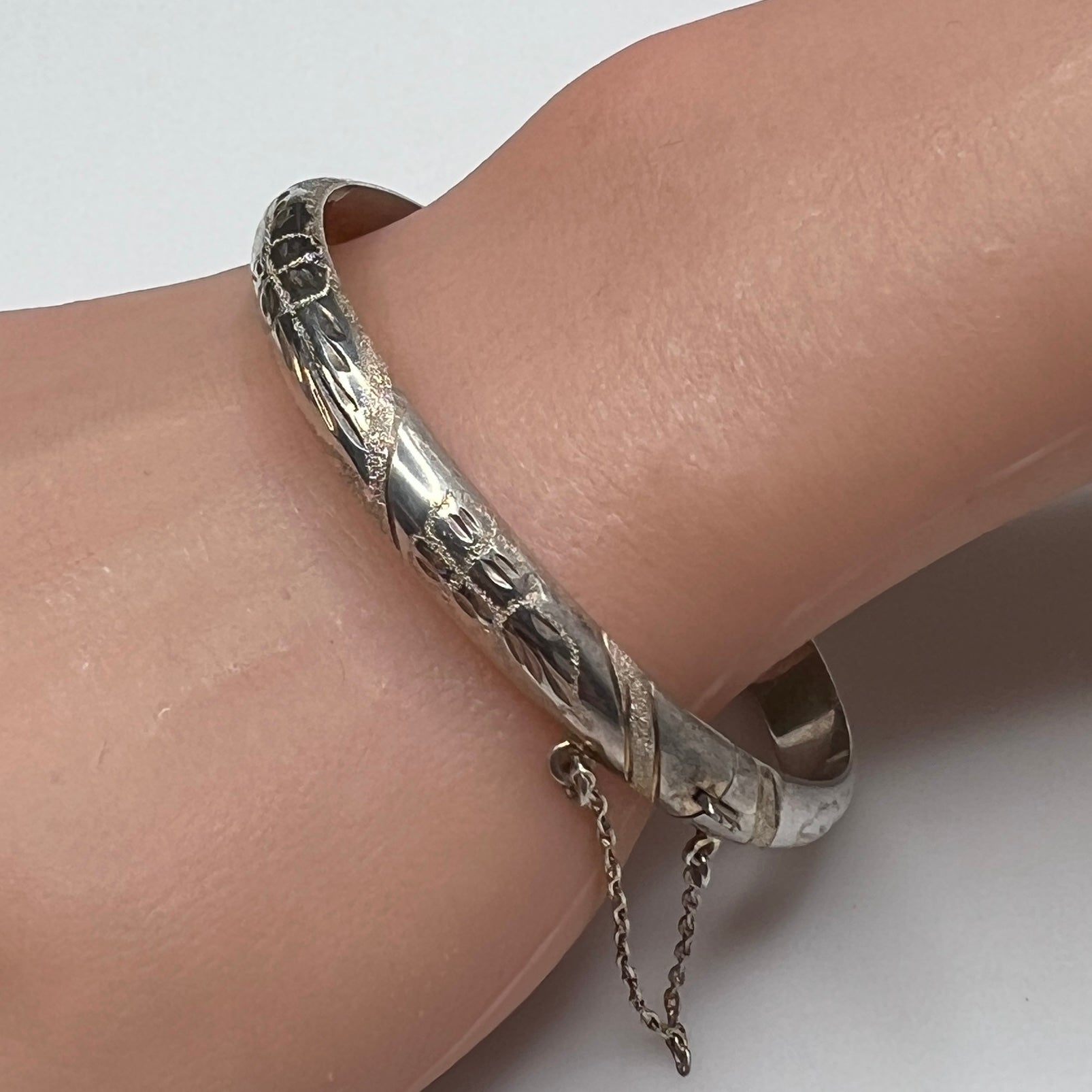Sterling silver oval bangle shown on wrist with polished floral etching