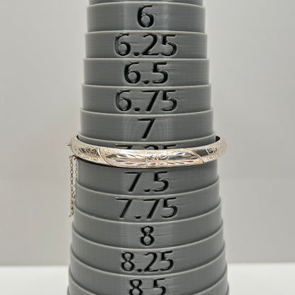 Close-up of silver bracelet with safety chain and textured detailing