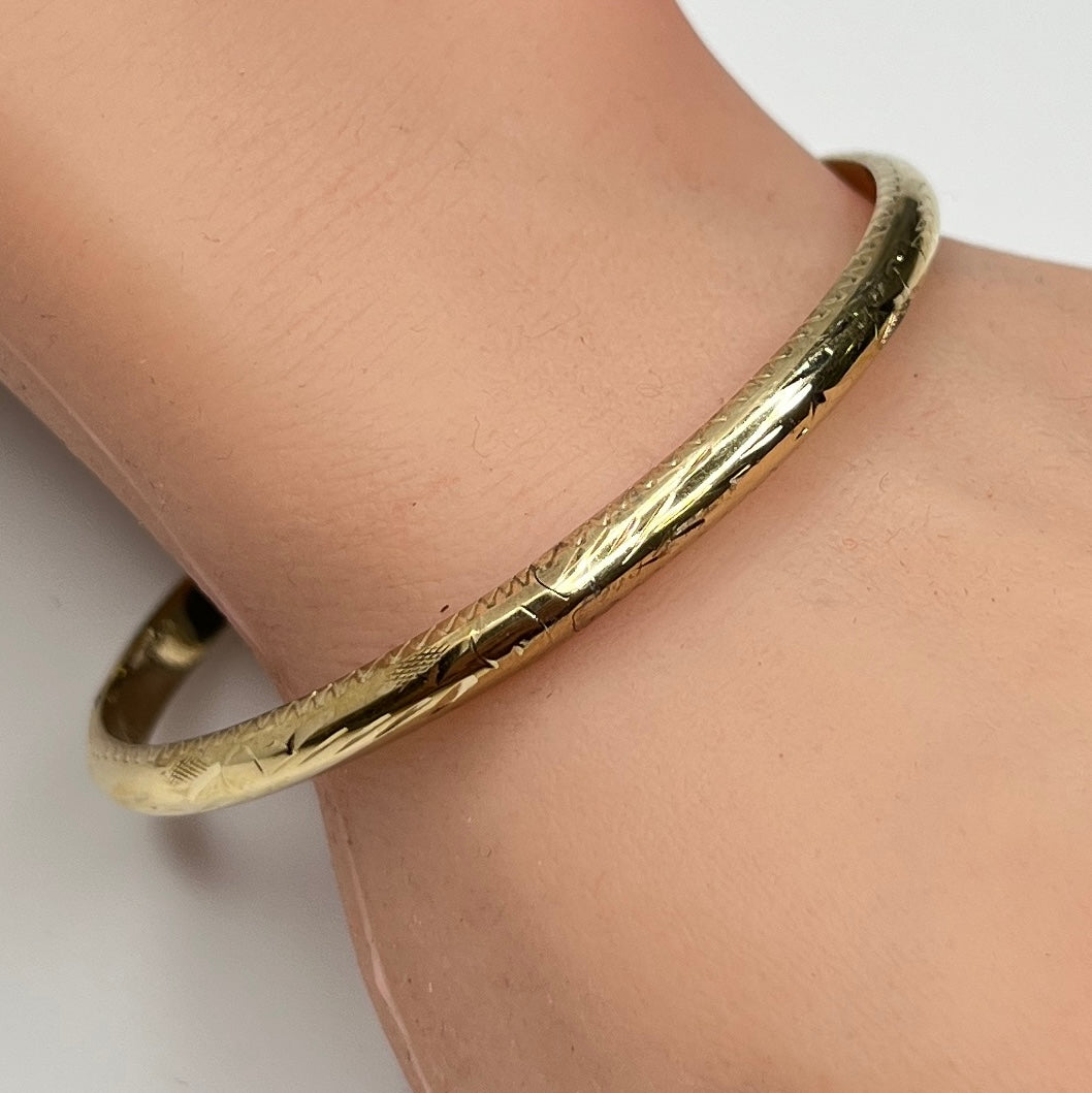 Gold vermeil etched bangle bracelet on wrist with floral design