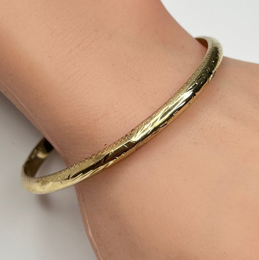 Gold vermeil etched bangle bracelet on wrist with floral design