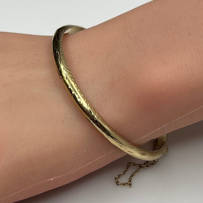 Gold vermeil etched bangle bracelet on wrist with floral design