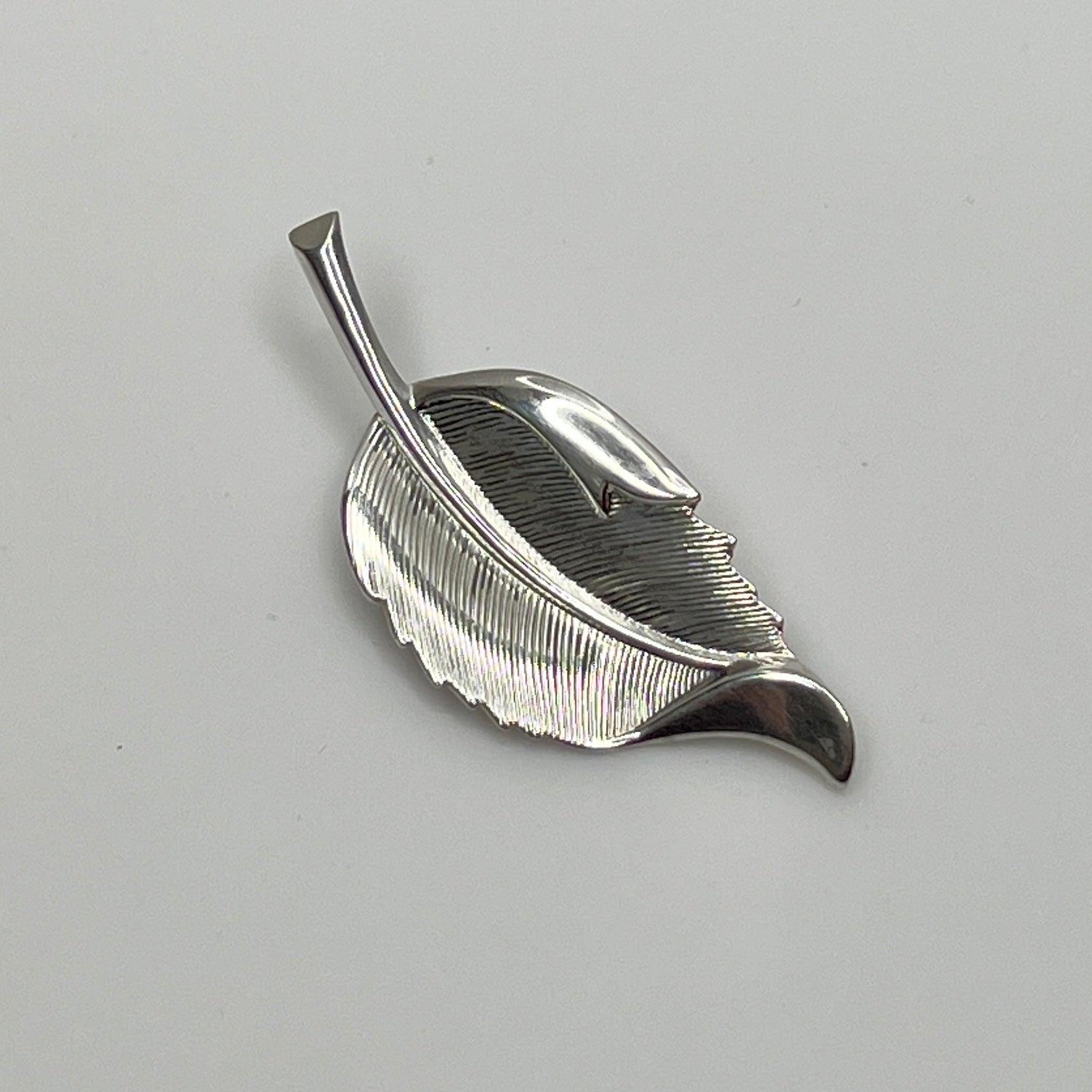 Close-up of sculptural mid-century silver brooch with curved leaf design