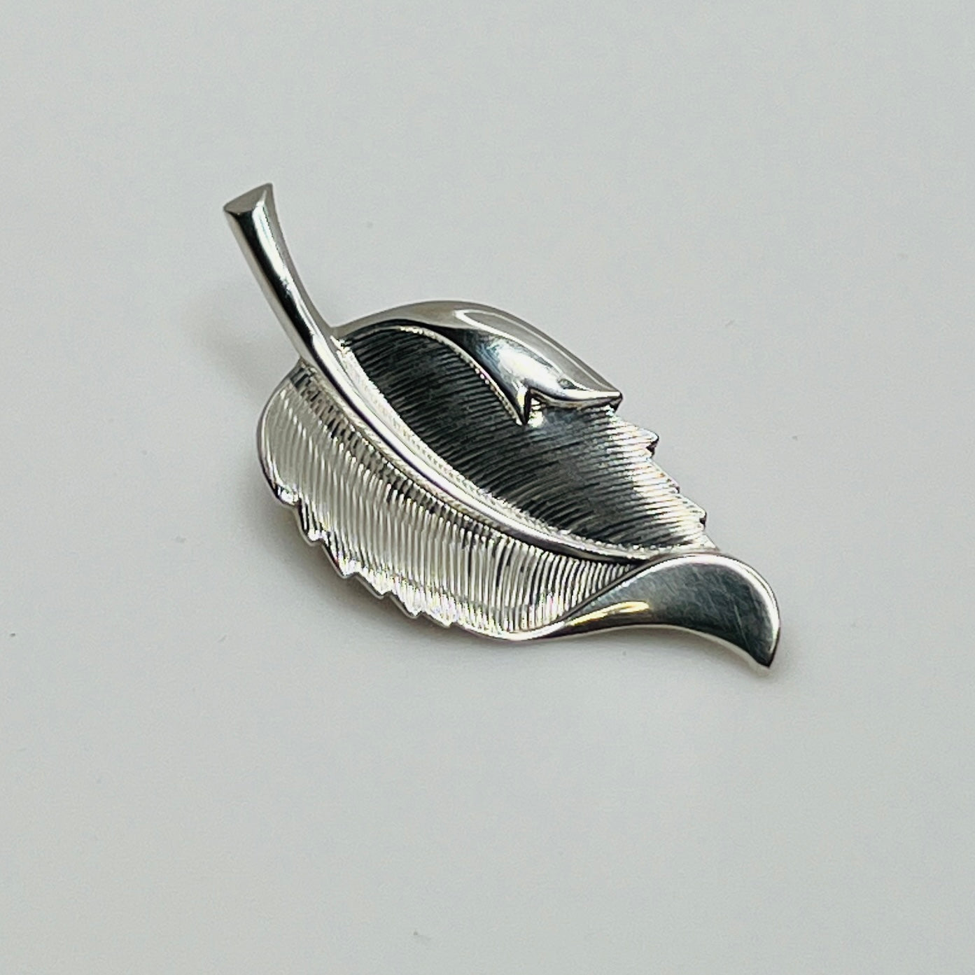 Close-up of sculptural mid-century silver brooch with curved leaf design