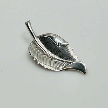 Close-up of sculptural mid-century silver brooch with curved leaf design