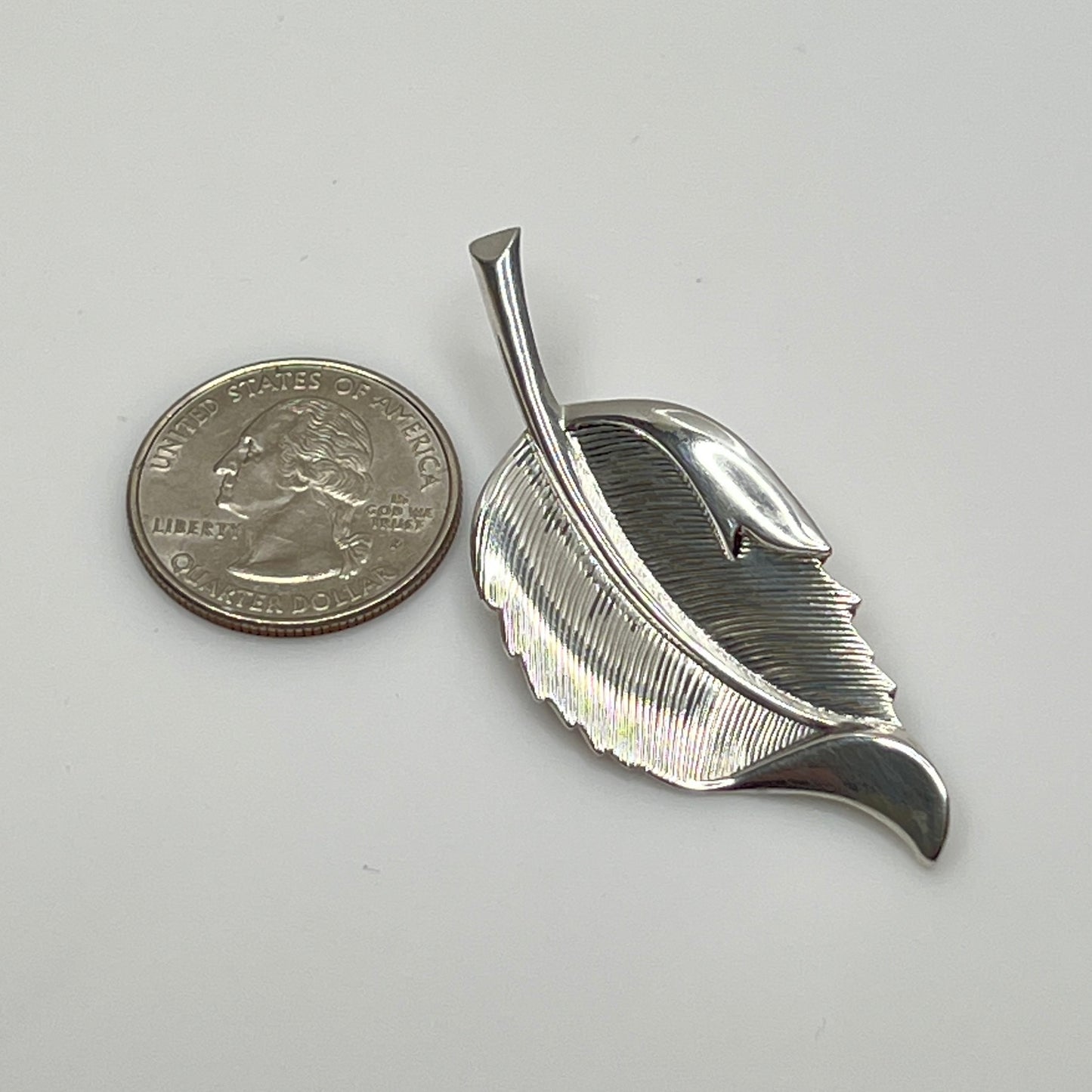 Close-up of sculptural mid-century silver brooch with curved leaf design