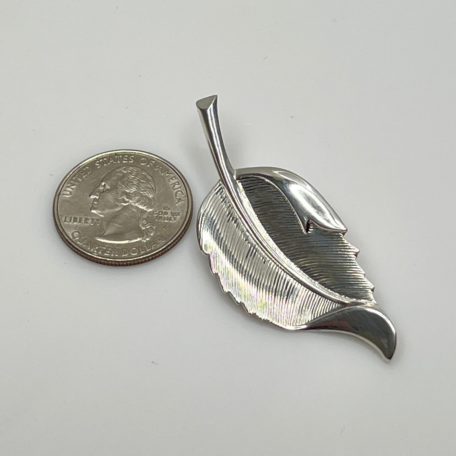 Close-up of sculptural mid-century silver brooch with curved leaf design