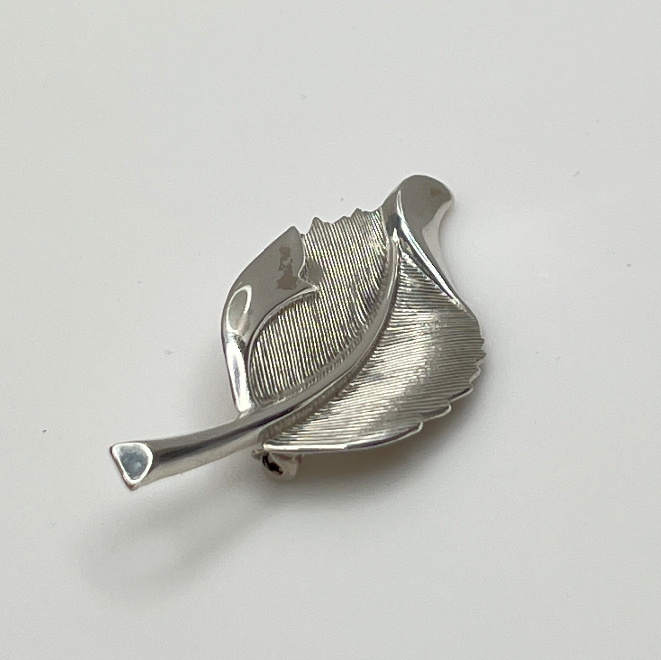Close-up of sculptural mid-century silver brooch with curved leaf design