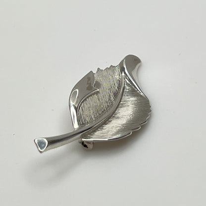 Close-up of sculptural mid-century silver brooch with curved leaf design