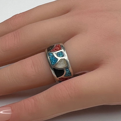 Sterling silver mosaic ring with turquoise, coral, onyx, and mother-of-pearl inlay on model’s hand