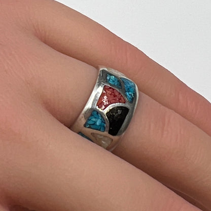 Sterling silver mosaic ring with turquoise, coral, onyx, and mother-of-pearl inlay on model’s hand