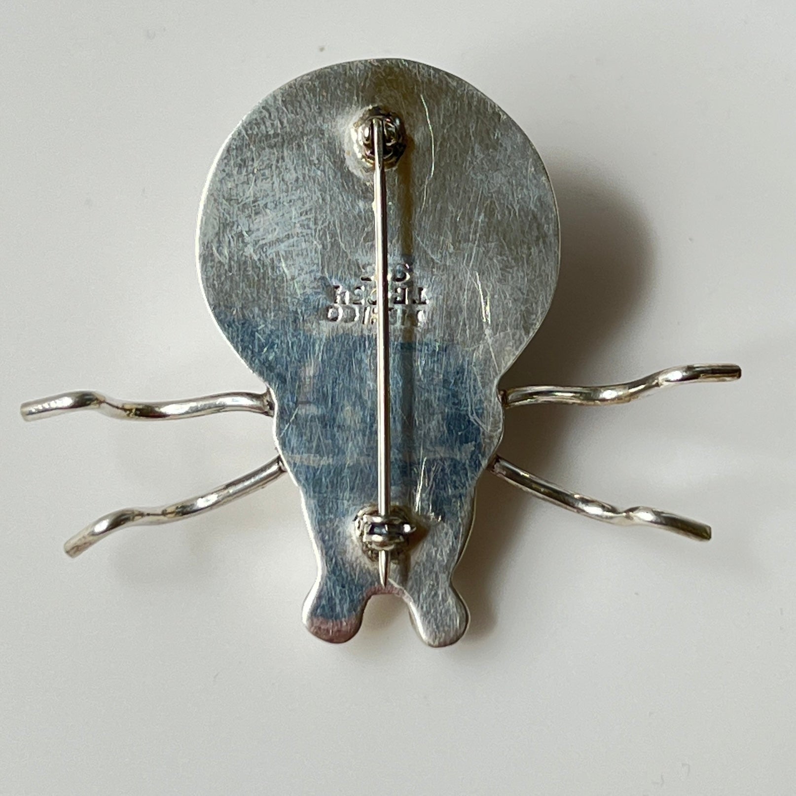 Sterling silver spider brooch with stylized body and curved legs