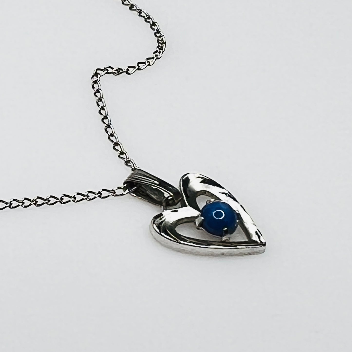 Close-up of sterling heart pendant with prong-set blue star sapphire