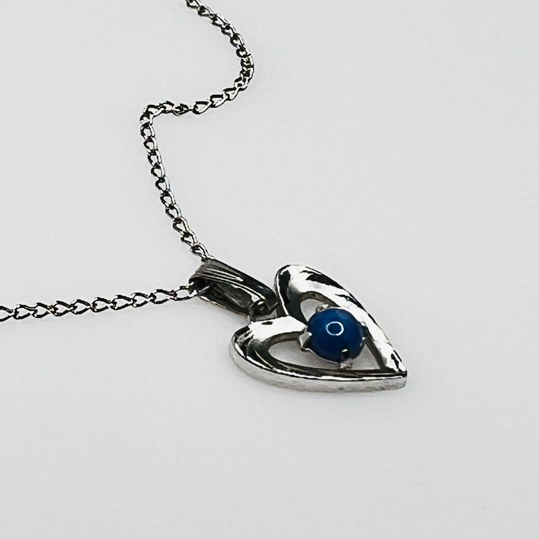 Close-up of sterling heart pendant with prong-set blue star sapphire