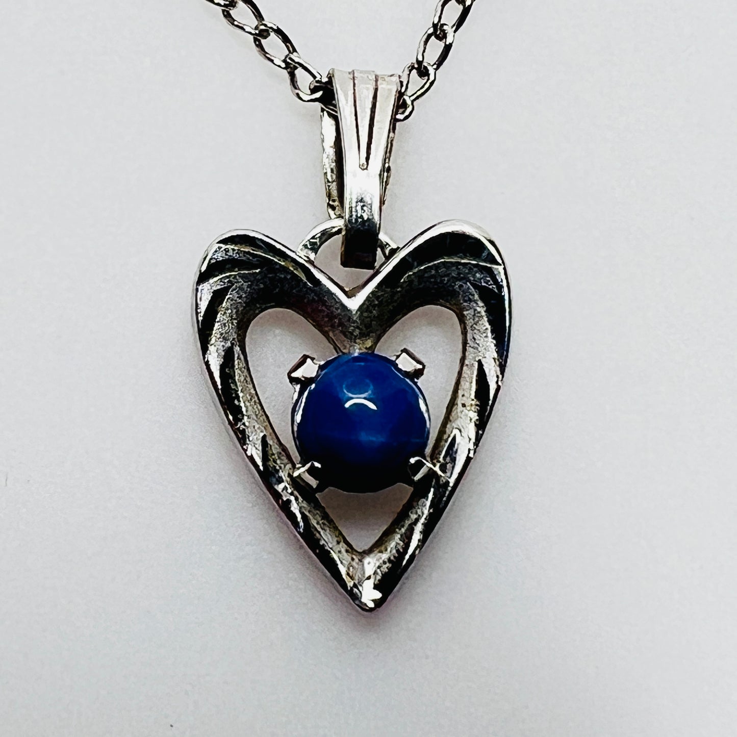 Close-up of sterling heart pendant with prong-set blue star sapphire