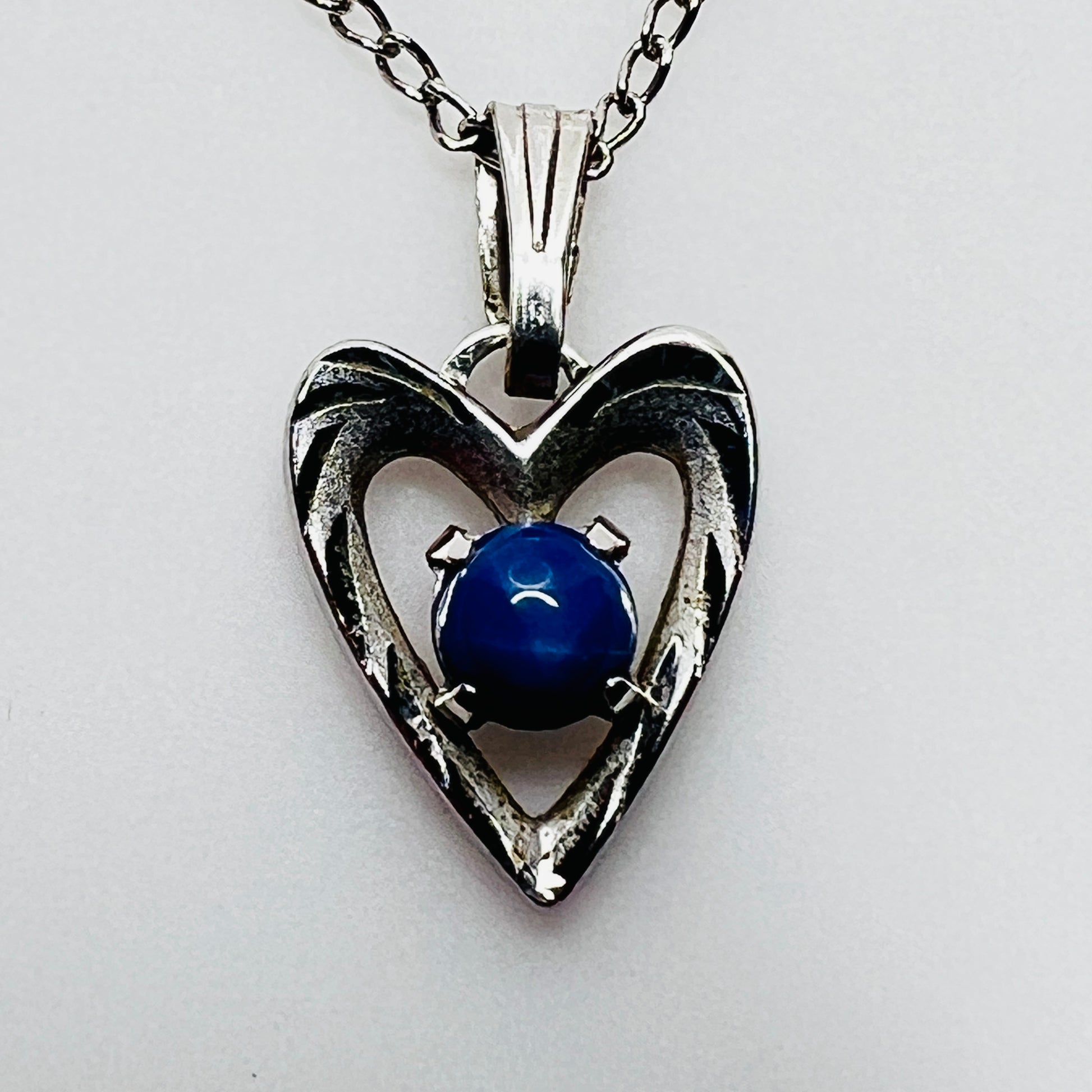 Close-up of sterling heart pendant with prong-set blue star sapphire