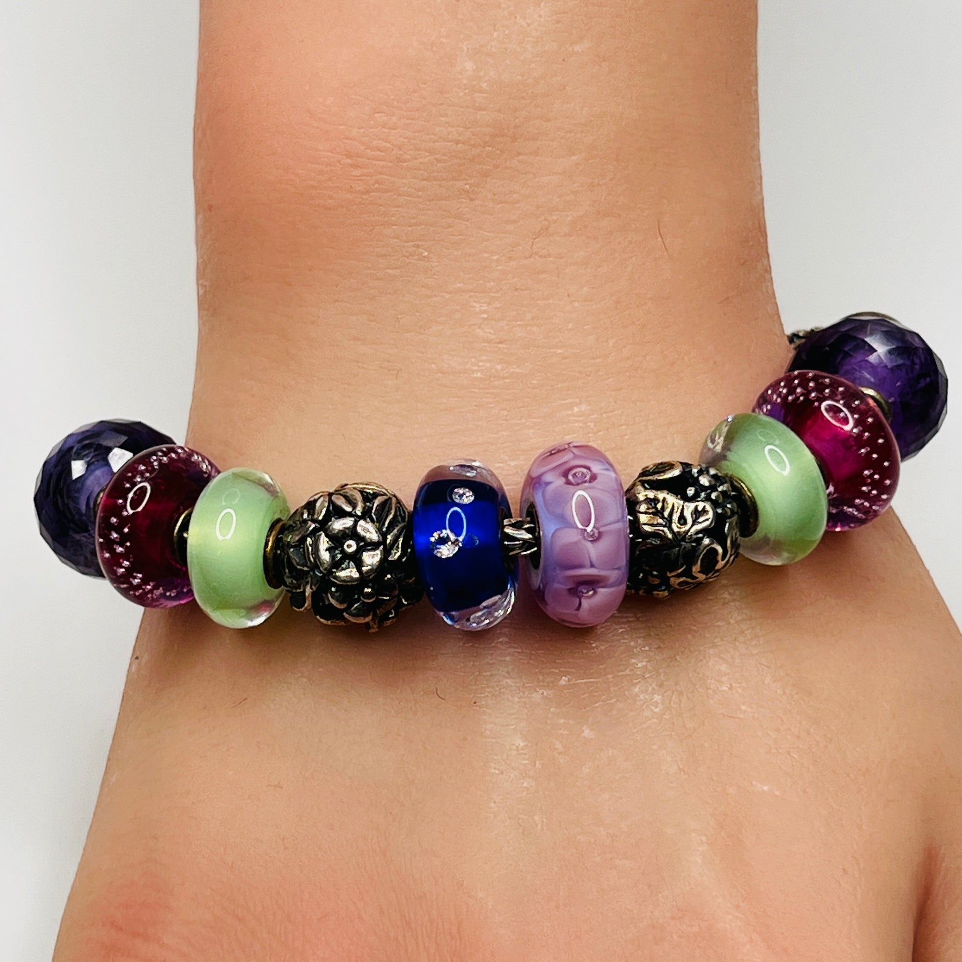 Close-up of sterling silver and glass charm bracelet with multicolored beads