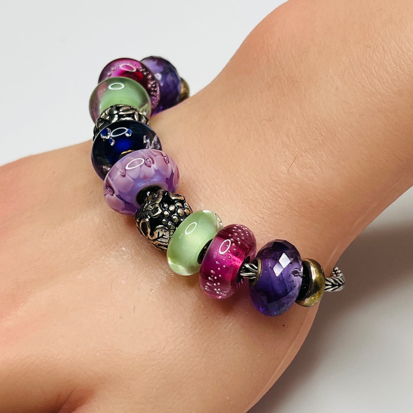 Close-up of sterling silver and glass charm bracelet with multicolored beads