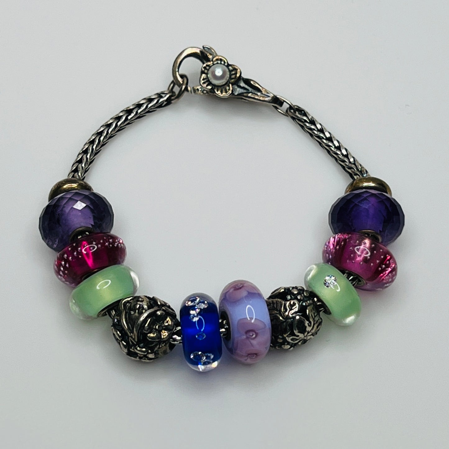 Close-up of sterling silver and glass charm bracelet with multicolored beads