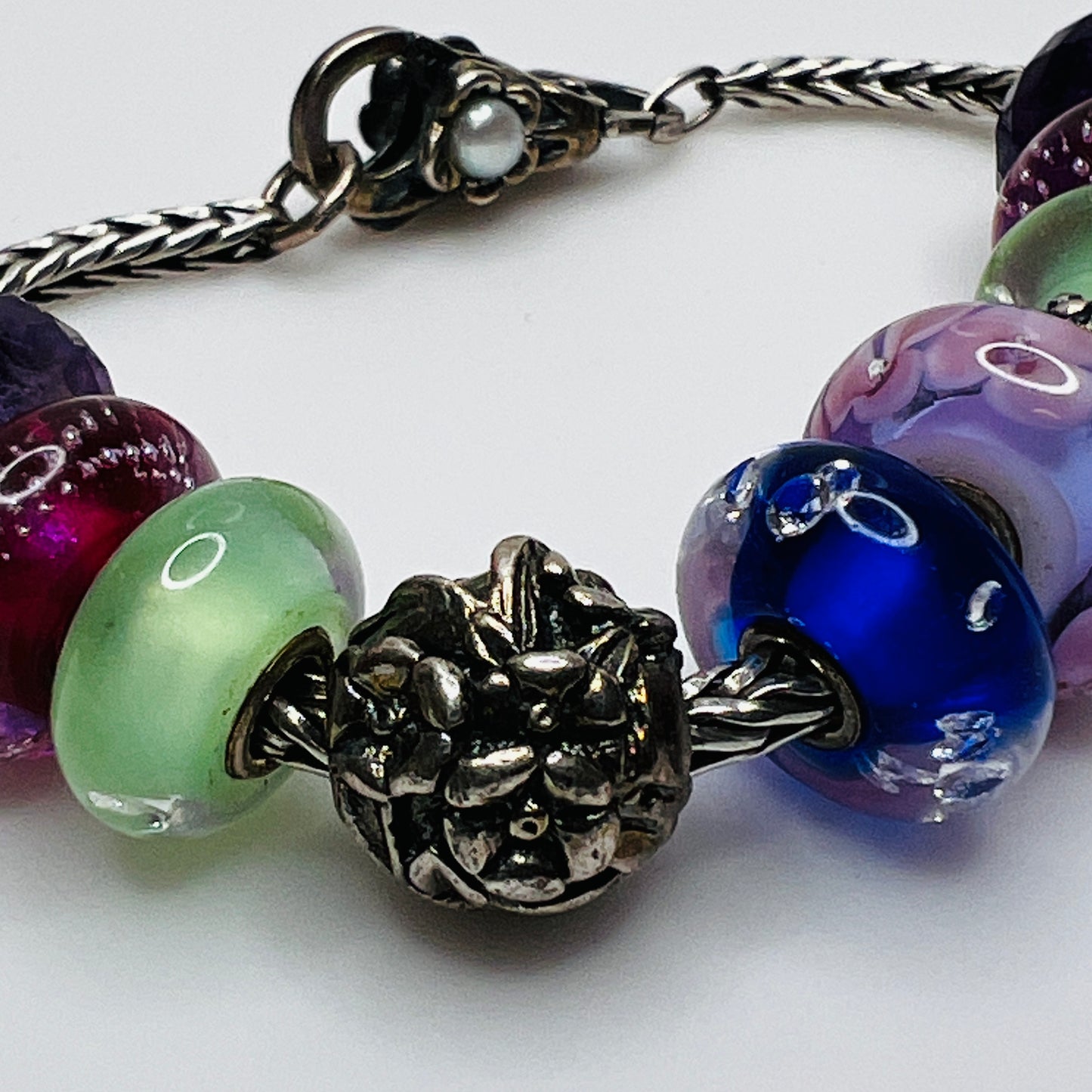 Close-up of sterling silver and glass charm bracelet with multicolored beads