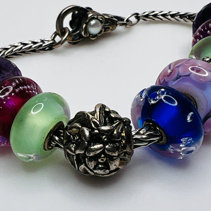 Close-up of sterling silver and glass charm bracelet with multicolored beads