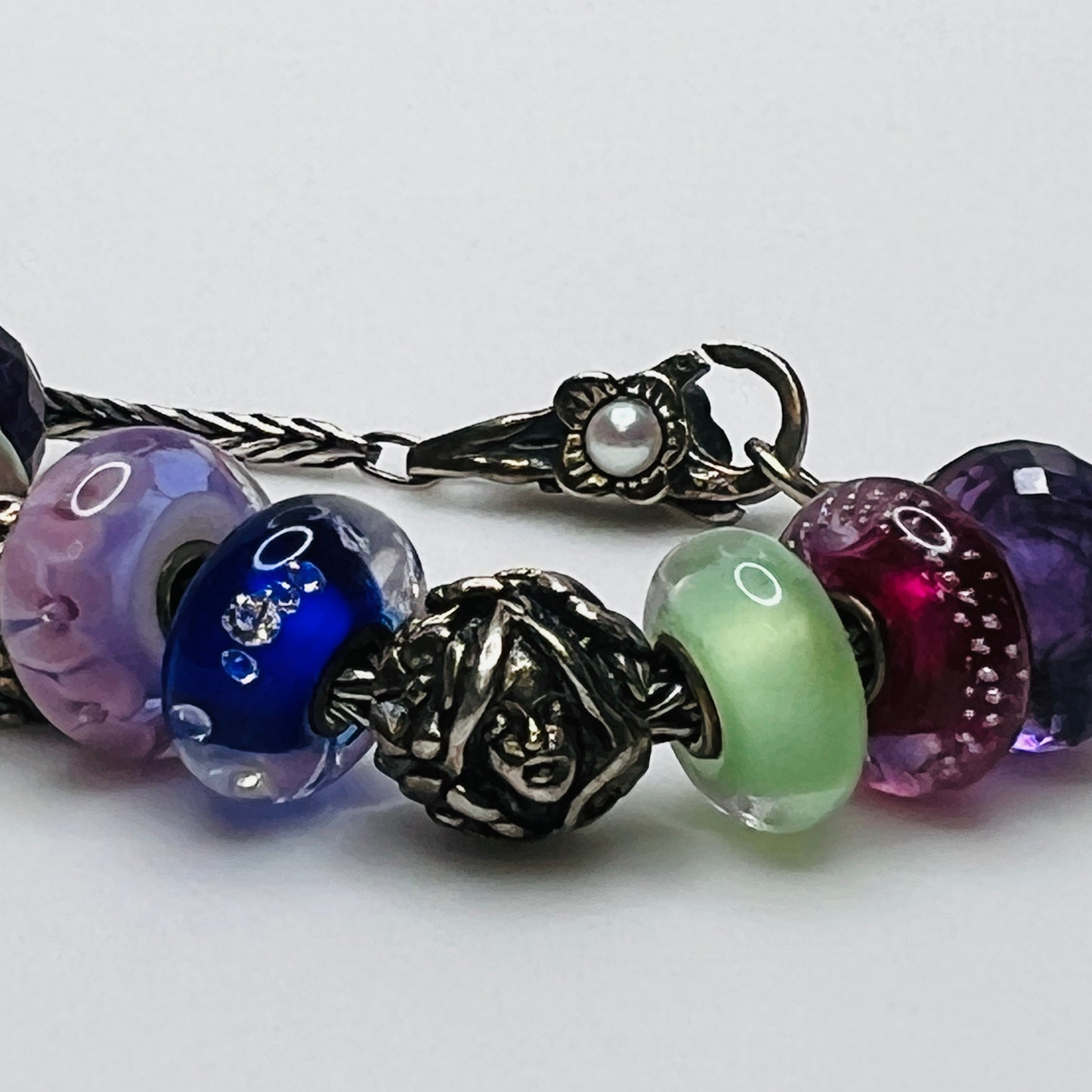 Close-up of sterling silver and glass charm bracelet with multicolored beads