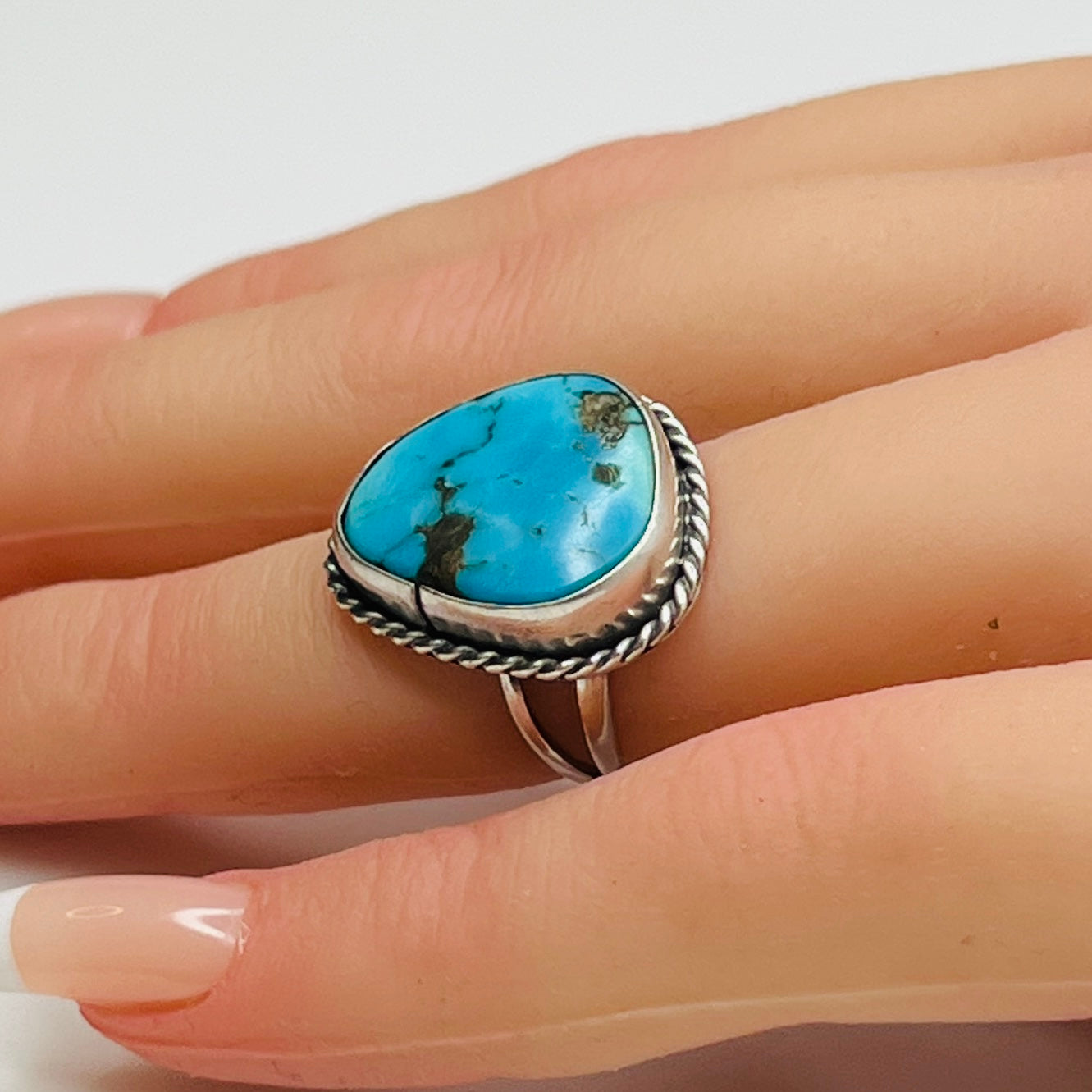Sterling silver turquoise ring worn on finger, teardrop shape