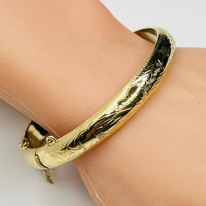 Gold vermeil etched bangle bracelet on wrist – floral engraved detail