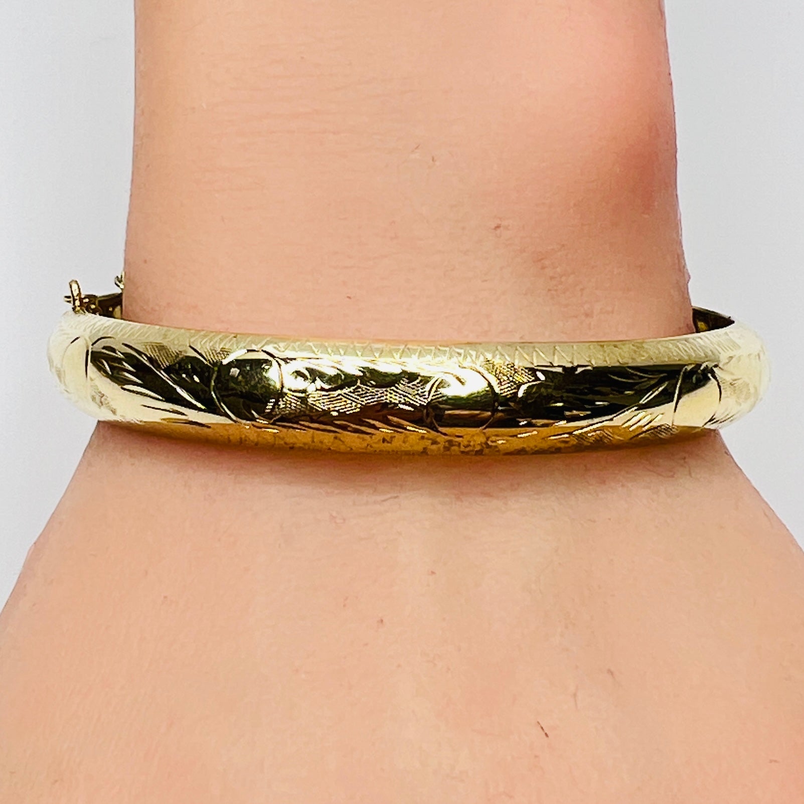 Gold vermeil etched bangle bracelet on wrist – floral engraved detail