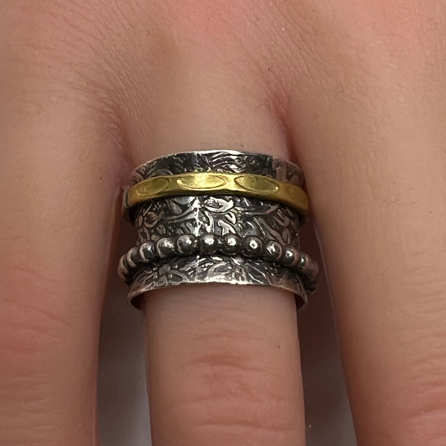 Close-up of oxidized silver ring on hand, showcasing spinning bands and textured detail