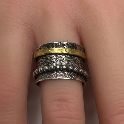 Close-up of oxidized silver ring on hand, showcasing spinning bands and textured detail