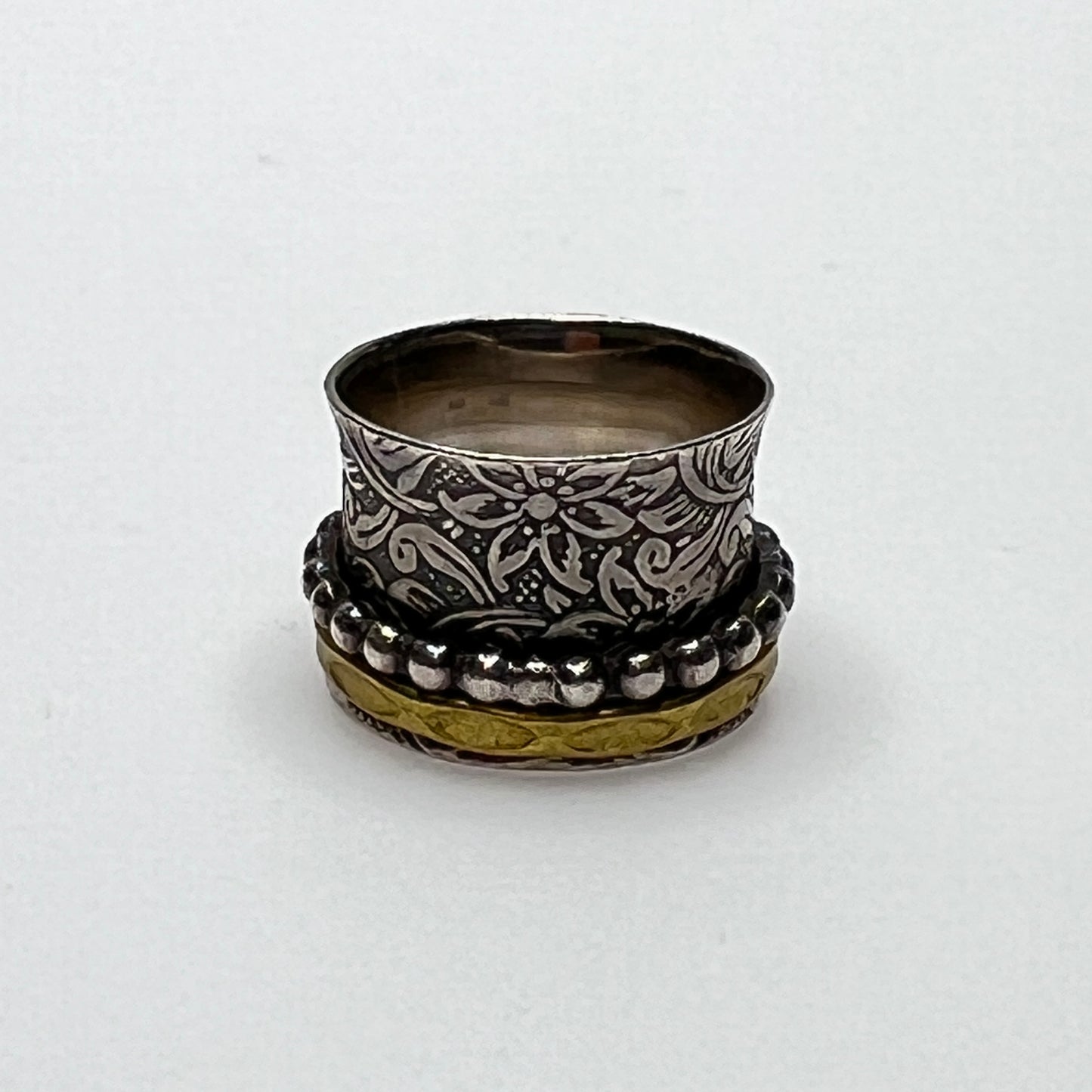 Wide sterling silver spinner ring with floral embossing, brass band, and beaded spinner