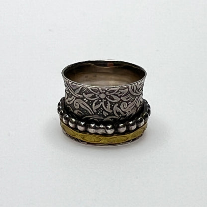 Wide sterling silver spinner ring with floral embossing, brass band, and beaded spinner