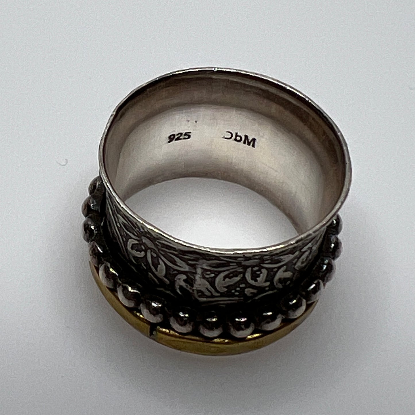 Wide sterling silver spinner ring with floral embossing, brass band, and beaded spinner